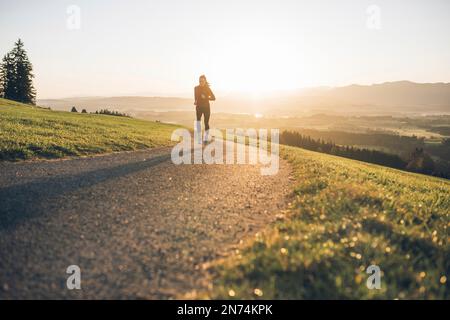 Profitriathleten laufen, Morgenatmosphäre, Sonnenaufgang, Auerberg, Allgäu, Bayern, Deutschland Stockfoto