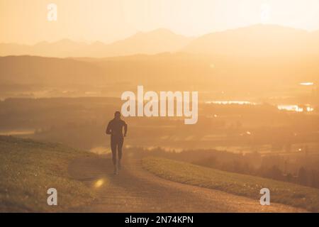 Profitriathleten laufen, Morgenatmosphäre, Sonnenaufgang, Auerberg, Allgäu, Bayern, Deutschland Stockfoto