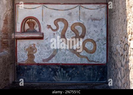 Wunderschönes, farbenfrohes Fresko mit einer gelben Schlange, einem Pfau und einer Büste einer Frau in einer Villa in Pompeji, Süditalien Stockfoto