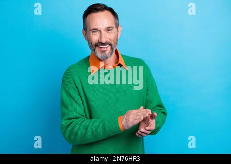 Fotoporträt eines erwachsenen, netten Mister, der klatscht Hände gratulieren Lächeln in stilvoller grüner Kleidung isoliert auf blauem Hintergrund Stockfoto