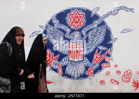 Teheran, Teheran, Iran. 9. Februar 2023. Zwei junge, getarnte iranische Frauen gehen am 09. Februar 2023 an einem Wandgemälde entlang der Mauer der ehemaligen US-Botschaft inmitten des Schnees in Teheran (Iran) vorbei. Der Leiter der Atomaufsicht der Vereinten Nationen unterstrich die Dringlichkeit, die diplomatischen Bemühungen zur Begrenzung des iranischen Atomprogramms wiederzubeleben, und erklärte, dass sich die Situation schnell verschlechtern könnte, wenn die Verhandlungen scheitern. (Kreditbild: © RouzbritFouladi/ZUMA Press Wire) NUR REDAKTIONELLE VERWENDUNG! Nicht für den kommerziellen GEBRAUCH! Stockfoto