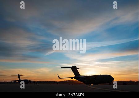 C-17 Globemaster III-Flugzeuge werden vom Sonnenaufgang auf der Fluglinie am 167. Airlift Wing, Martinsburg, West Virginia, am 5. Februar 2023 umrissen. Die C-17 ist das flexibelste Frachtflugzeug der Air Force. Sie kann Truppen und Fracht transportieren, taktische Lufttransport- und Luftabwurfeinsätze durchführen und Patienten während der aeromedizinischen Evakuierung transportieren. (USA Air National Guard Foto von Tech Sgt. Timothy Sencindiver) Stockfoto