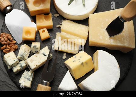 Käseplatte mit Spezialmessern und Gabel auf schwarzem Tisch, flach liegend Stockfoto