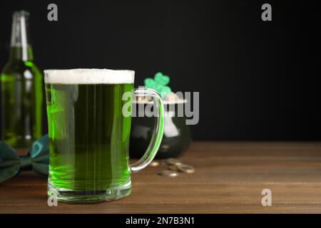 Grünbier und St. Patrick's Day-Einrichtung auf Holztisch vor schwarzem Hintergrund. Platz für Text Stockfoto