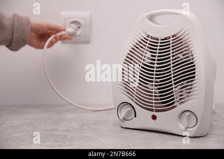 Frauen schließen moderne elektrische Heizlüfter in Innenräumen an, konzentrieren sich auf das Gerät. Platz für Text Stockfoto