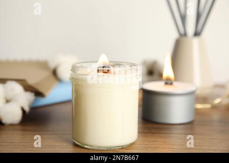 Brennende Kerze mit Holzdocht auf dem Tisch Stockfoto