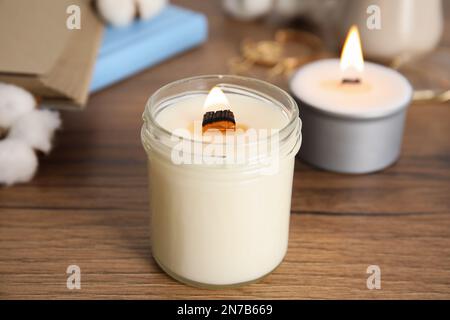 Brennende Kerze mit Holzdocht auf dem Tisch Stockfoto
