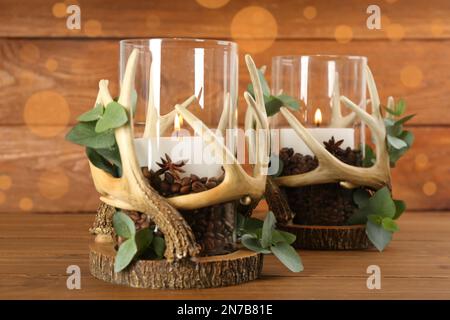 Stilvolle Halter mit brennenden Kerzen, Kaffeebohnen und Eukalyptus auf Holztisch Stockfoto