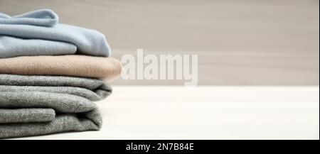 Ein Stapel Kaschmirbekleidung auf einem Holztisch, Platz für Text. Bannerdesign Stockfoto