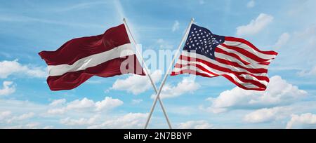 Zwei überkreuzte Flaggen USA und Lettland winken im Wind am bewölkten Himmel. Beziehungskonzept, Dialog, Reisen zwischen zwei Ländern. Stockfoto