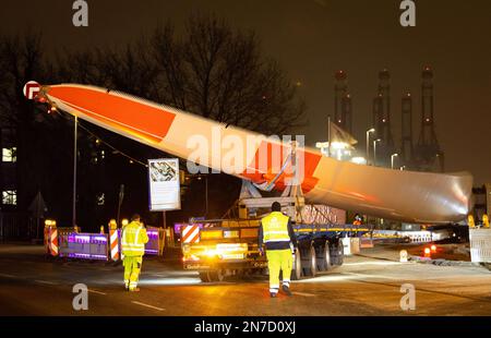 Hamburg, Deutschland. 10. Februar 2023. Ein Schwerlasttransport mit Rotorblättern für eine neue Windturbine ist auf dem Weg von der Autobahnausfahrt Waltershof im Hamburger Hafen zur Kläranlage Dradenau. Drei schwere Lkw brachten am Samstagabend große Teile einer neuen Windturbine nach Hamburg-Waltershof. Nach Angaben des Betreibers der Kläranlage Hamburg Wasser wird die neue Windturbine eine Leistung von 3,6 Megawatt haben und jährlich 9.000 Megawatt-Stunden Strom liefern. Kredit: Christian Charisius/dpa/Alamy Live News Stockfoto