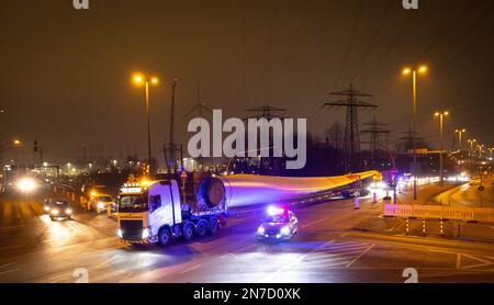 Hamburg, Deutschland. 10. Februar 2023. Ein Schwerlasttransport mit Rotorblättern für eine neue Windturbine ist auf dem Weg von der Autobahnausfahrt Waltershof im Hamburger Hafen zur Kläranlage Dradenau. Drei schwere Lkw brachten am Samstagabend große Teile einer neuen Windturbine nach Hamburg-Waltershof. Nach Angaben des Betreibers der Kläranlage Hamburg Wasser wird die neue Windturbine eine Leistung von 3,6 Megawatt haben und jährlich 9.000 Megawatt-Stunden Strom liefern. Kredit: Christian Charisius/dpa/Alamy Live News Stockfoto