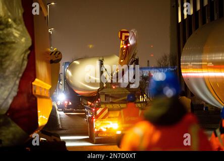 Hamburg, Deutschland. 10. Februar 2023. Ein Schwerlasttransport mit Rotorblättern für eine neue Windturbine ist auf dem Weg von der Autobahnausfahrt Waltershof im Hamburger Hafen zur Kläranlage Dradenau. Drei schwere Lkw brachten am Samstagabend große Teile einer neuen Windturbine nach Hamburg-Waltershof. Nach Angaben des Betreibers der Kläranlage Hamburg Wasser wird die neue Windturbine eine Leistung von 3,6 Megawatt haben und jährlich 9.000 Megawatt-Stunden Strom liefern. Kredit: Christian Charisius/dpa/Alamy Live News Stockfoto