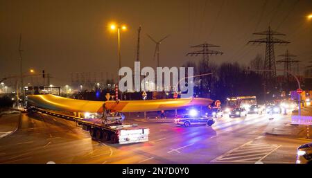 Hamburg, Deutschland. 10. Februar 2023. Ein Schwerlasttransport mit Rotorblättern für eine neue Windturbine ist auf dem Weg von der Autobahnausfahrt Waltershof im Hamburger Hafen zur Kläranlage Dradenau. Drei schwere Lkw brachten am Samstagabend große Teile einer neuen Windturbine nach Hamburg-Waltershof. Nach Angaben des Betreibers der Kläranlage Hamburg Wasser wird die neue Windturbine eine Leistung von 3,6 Megawatt haben und jährlich 9.000 Megawatt-Stunden Strom liefern. Kredit: Christian Charisius/dpa/Alamy Live News Stockfoto