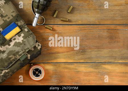 Taktische Ausrüstung, Militäruniform und ukrainische Armee auf Holztisch, flach liegend. Platz für Text Stockfoto