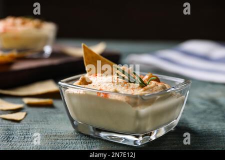 Köstlicher hausgemachter Hummus in Glasschüssel auf Holztisch Stockfoto