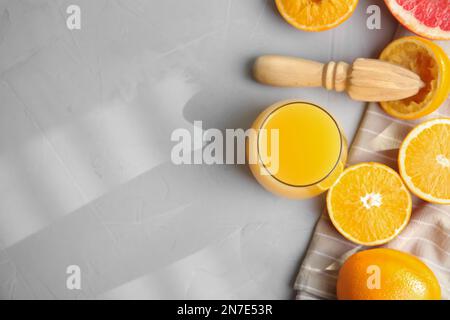 Frisch zubereiteter Saft, Orangen und Reibahle auf hellgrauem Tisch, flach gelegt. Platz für Text Stockfoto