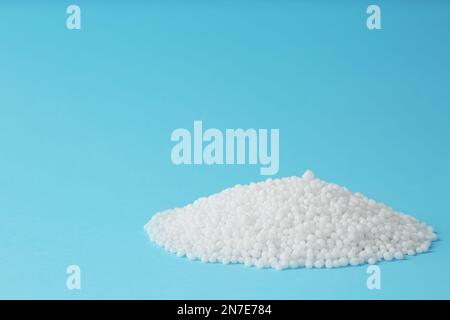 Ammoniumnitrat-Pellets auf hellblauem Hintergrund, Platz für Text. Mineraldünger Stockfoto