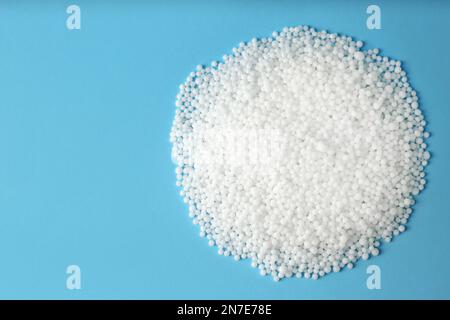 Ammoniumnitrat-Pellets auf hellblauem Hintergrund, flach liegend mit Platz für Text. Mineraldünger Stockfoto