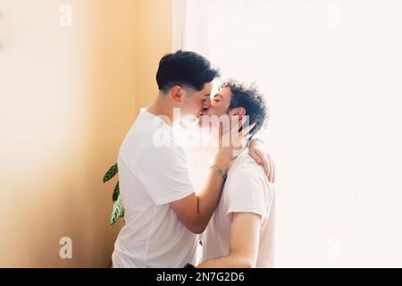 Zwei schwule Männer, die weiße T-Shirts tragen und sich romantisch auf den Mund küssen. LGBT-Beziehung Stockfoto