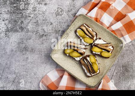 Sandwiches mit Sprossen, Quark und Gurken auf einem quadratischen Teller auf dunklem Grund. Draufsicht, flach liegend Stockfoto