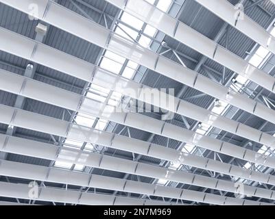 Beleuchtung und Lüftungsanlage in langer Linie an der Decke des Industriegebäudes. Ausstellungshalle. Deckenfabrikbau Stockfoto