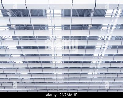 Beleuchtung und Lüftungsanlage in langer Linie an der Decke des Industriegebäudes. Ausstellungshalle. Deckenfabrikbau Stockfoto