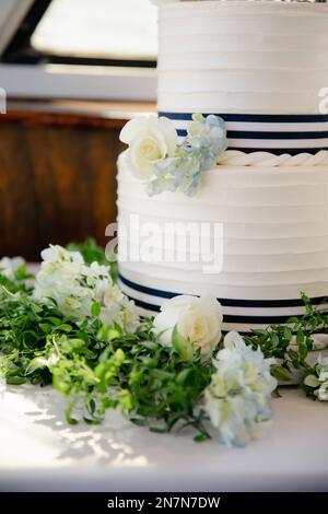 Weiße Hochzeitstorte mit blauer Hortensien und Rosendekoration, zweistufige Wüste im maritimen Stil. Stockfoto