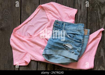 Pink Damen T-Shirt flache ijins Shorts auf rustikalem braunem Hintergrund, Damenbekleidung, Mode Stockfoto