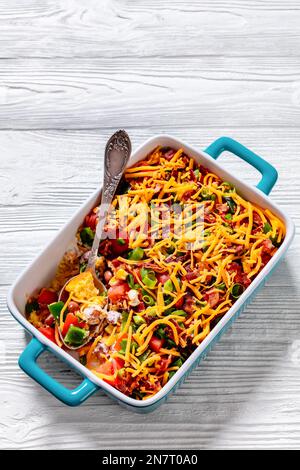 pinto Beans Speck Maisbrotsalat mit Tomaten, Paprika, Mais und Cheddar Käse in rechteckiger Schüssel auf weißem Holztisch mit Löffel, vertikale Ansicht fr Stockfoto