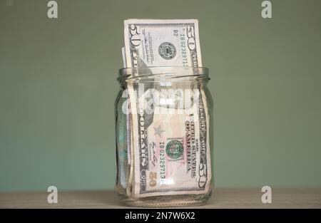 50 Dollar liegen in einem Glasglas auf dem Tisch, Finanzthema Stockfoto