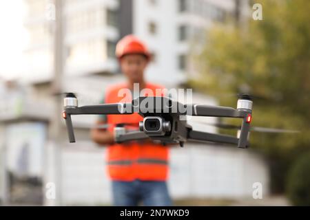 Bauarbeiter, die Drohne mit Fernsteuerung auf der Baustelle bedienen. Luftaufnahmen Stockfoto