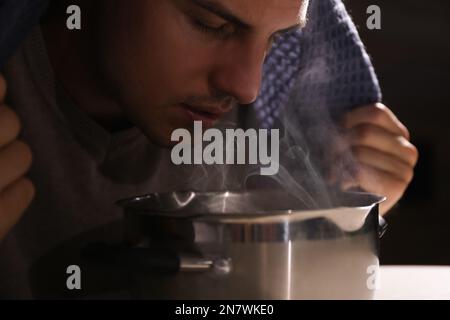 Ein Mann mit Karomuster inhaliert über dem Saucetopf, Nahaufnahme Stockfoto