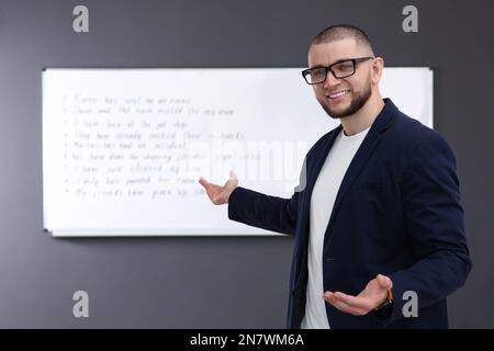 Englischlehrer in der Nähe des Whiteboards mit Aufgabe im Unterricht Stockfoto