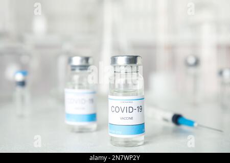 Fläschchen und Spritze mit Coronavirus-Impfstoff auf dem Lichttisch Stockfoto