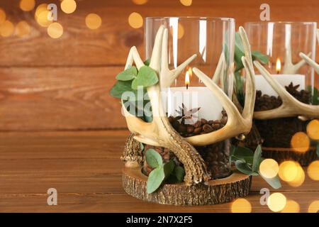 Stilvolle Halter mit brennenden Kerzen, Kaffeebohnen und Eukalyptus auf Holztisch. Platz für Text Stockfoto
