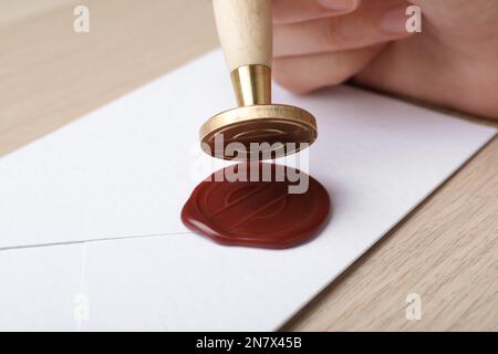 Frau hat den Umschlag am Holztisch versiegelt, Nahaufnahme Stockfoto