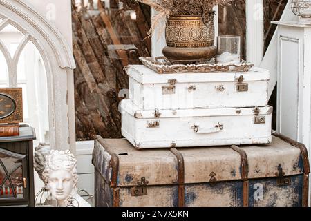 Ein Haufen altmodischer Koffer in Form eines Turms mit alter Vase oben am Fenster in einem schäbigen, schicken Innenraum im französischen Landhaus der Provence Stockfoto