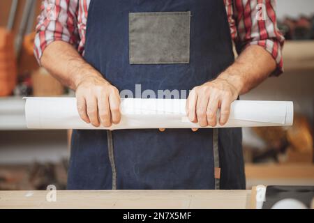 Nahaufnahme Hand des Baumeisters mit Papierrolle für Smart Home Improvement-Projektkonzept Stockfoto