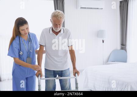 Physiotherapeut-Krankenschwester, die den älteren Patienten unterstützt und Beinmuskelerholung mit Gehhilfe praktiziert Stockfoto