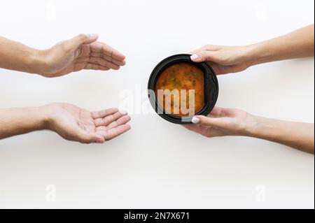 Eine Suppenbedürftige Person, die eine Schüssel von der Hand gibt Stockfoto