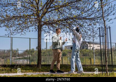 Junges Paar in Liebesfreunden in zwangloser Kleidung, das gemeinsam im Sommerpark spazierengeht Stockfoto