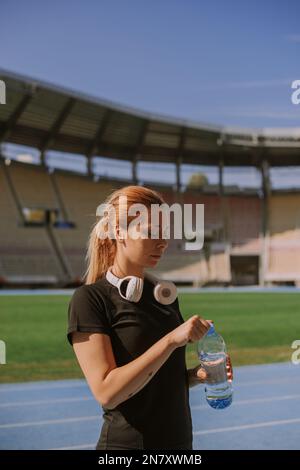 Ein hübsches, sportliches blondes Mädchen trinkt Wasser Stockfoto