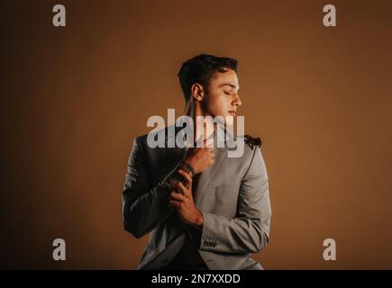 Ein hübscher Mann, der mit seiner Tarantel posiert, während er im Studio sitzt Stockfoto