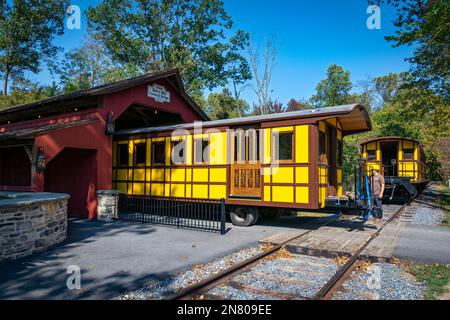 Elizabethtown, Pennsylvania, 7. Oktober 2020 - Installation eines neuen gelben Passagiers Antique Coach Thru a Cover Bridge on a Railroad Track Stockfoto