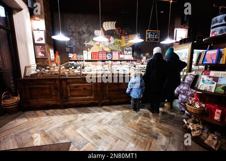 Ternopil, Ukraine - 10. Februar 2023: Mutter und drei Kinder kaufen am Winterabend Süßigkeiten in der Schokoladenwerkstatt. Stockfoto