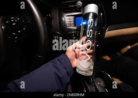 Ternopil, Ukraine - 10. Februar 2023: Man hält eine Voss-Wasserflasche am Auto. Stockfoto