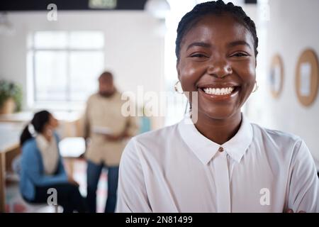 Ich behalte den Preis im Auge. Porträt einer selbstbewussten jungen Geschäftsfrau, die in einem modernen Büro mit ihren Kollegen im Hintergrund arbeitet. Stockfoto