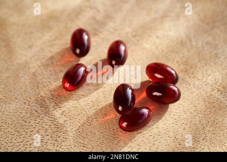 Rote Krill-Ölpillen auf einem Holztisch Stockfoto