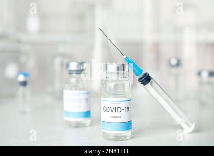 Fläschchen und Spritze mit Coronavirus-Impfstoff auf dem Lichttisch Stockfoto
